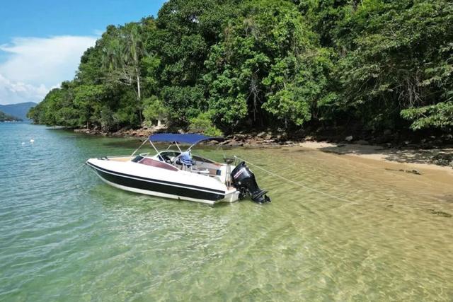 Lancha ancorada em água transparente numa praia da baía