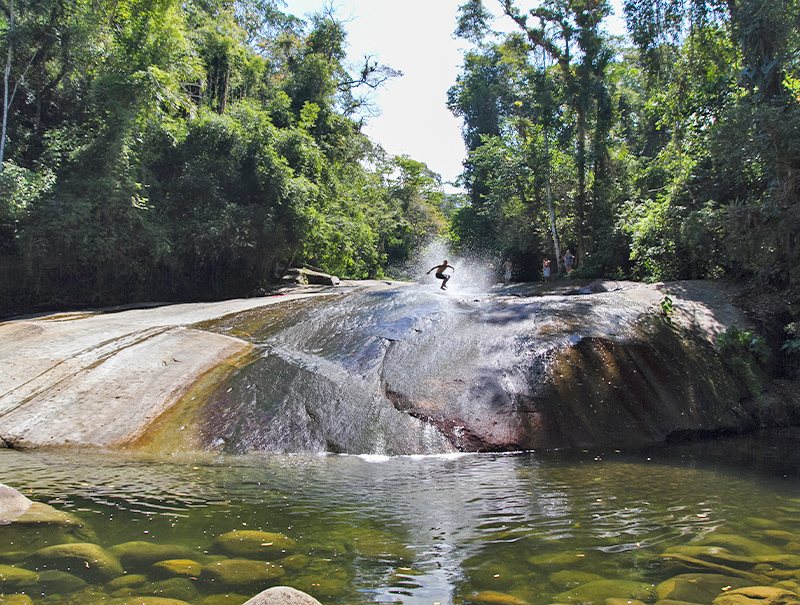 Pessoa descendo a laje de pedra lisa do Tobogã até o poço
